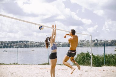 Spor ve aktif yaşam teması. Genç oyuncular voleybol oynar. Plaj oyun alanı.