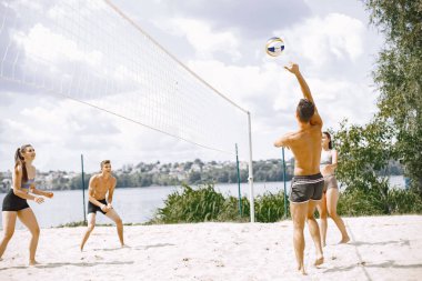 Spor ve aktif yaşam teması. Genç oyuncular voleybol oynar. Plaj oyun alanı.