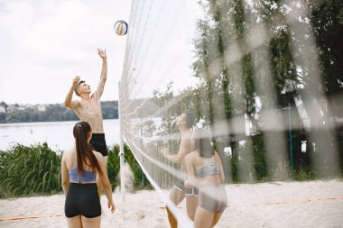 Spor ve aktif yaşam teması. Genç oyuncular voleybol oynar. Plaj oyun alanı.