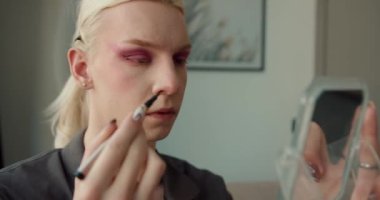 Yatak odasında makyaj yapan genç bir adamın yakın çekimi var. Lgbtq topluluk kavramı.
