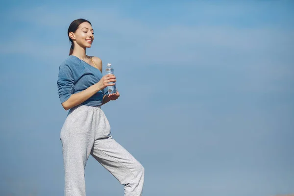 stock image Beautiful girl standing on a sky background. Woman in a blue sweater. Lady with in her hands