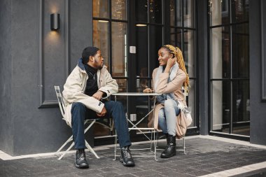 Dışarıda oturan iki genç insan. Afrikalı çift birlikte vakit geçirmekten zevk alıyor..