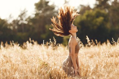 Woman in a summer field. Brunette in a spots suit. Girl on a sunset background.