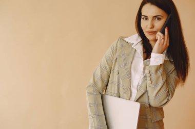 Stüdyoda bir kadın. Dizüstü bilgisayarı olan bir bayan. Kahverengi ceketli esmer.