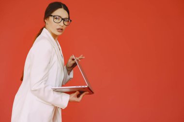 Stüdyoda bir kadın. Dizüstü bilgisayarı olan bir bayan. Beyaz takım elbiseli esmer.