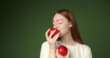 Beyaz tişörtlü, elinde elma tutan tatlı bir kız. Sağlıklı beslenme konsepti. Meyve ve sebze tüketimini tavsiye eder. İzole edilmiş.