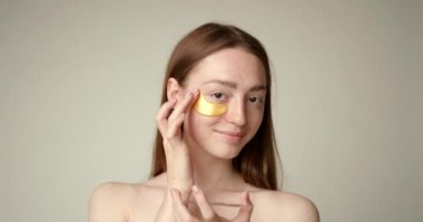 Güzel kız gözlerinin altına altın kolajen bantları yapıştırıyor. Kadın yüz tedavisi. Kozmetik, güzellik ve kaplıca .