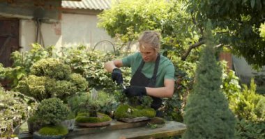 Genç adam bahçede rahatla. Bitkileri, çiçekleri ve ölü yaprakları kesmeyi önemsiyor. Doğa, hobi konsepti.
