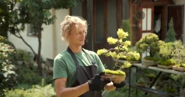Genç adam bahçede rahatla. Bitkileri, çiçekleri ve ölü yaprakları kesmeyi önemsiyor. Doğa, hobi konsepti.
