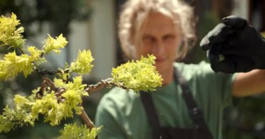 Genç adam bahçede rahatla. Bitkileri, çiçekleri ve ölü yaprakları kesmeyi önemsiyor. Doğa, hobi konsepti.