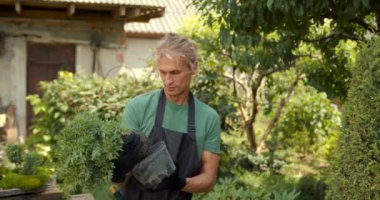 Genç adam bahçede rahatla. Bitkileri, çiçekleri ve ölü yaprakları kesmeyi önemsiyor. Doğa, hobi konsepti.