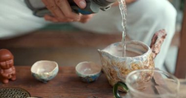 Genç bir adam geleneksel Çin çay seremonisi sanatını öğreniyor. Bambu tepsisinde özel bir cam kasede olgunlaşmış çiğ çay demler.