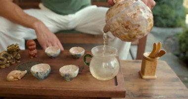 Genç bir adam geleneksel Çin çay seremonisi sanatını öğreniyor. Bambu tepsisinde özel bir cam kasede olgunlaşmış çiğ çay demler.