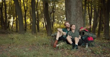 Doğa, yürüyüş ve bir çift ormanda macera peşinde rahatlar ve ağacın altında otururlar. Sağlık, mutlu erkek ve kadın ağaçlarla, fitness ve özgürlükle ormanda dinleniyor..