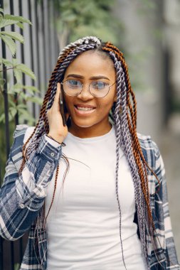 Şehir parkında gülümseyen afro saçlı genç siyahi kadın. Karışık bir kız şehirde yürüyor..