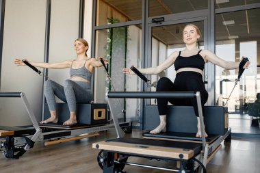 Özel bir ekipman üzerinde egzersiz yapan iki hamile kadın. Spor salonunda çalışan sağlıklı kadınlar. Gri ve siyah spor ayakkabı giyen kadınlar..