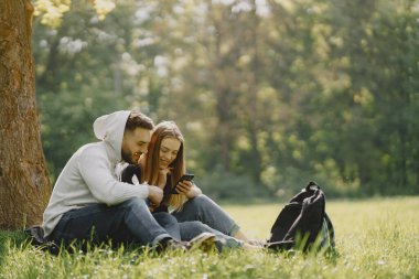 Yaz ormanındaki turistler. Siyah tişörtlü kız. Adam telefon kullanıyor..