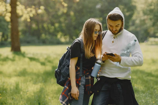 stock image Tourists in a summer forest. Girl in a black t-shirt. Man use a phone.