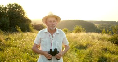 Dürbünle bakan bir adam güzel bir çayır arka planında yaban hayatı arıyor..