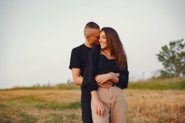 Couple in a field. Woman in a black blouse. Sunset background.