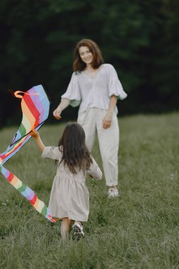 Gülen bir kadın ve parkta küçük sevimli bir bebek. Parkta renkli uçurtmayla aile oyunu.