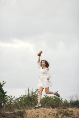 Yaz tarlasında bir kadın. Beyaz elbiseli esmer. Müzik hoparlörü olan kız.