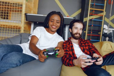 Beyaz tişörtlü siyah kız. Video oyunu oynayan bir çift. İnsanlar joystick kullanır.