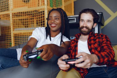 Beyaz tişörtlü siyah kız. Video oyunu oynayan bir çift. İnsanlar joystick kullanır.