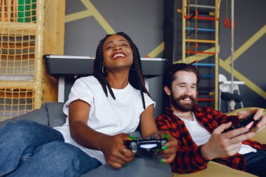 Beyaz tişörtlü siyah kız. Video oyunu oynayan bir çift. İnsanlar joystick kullanır.