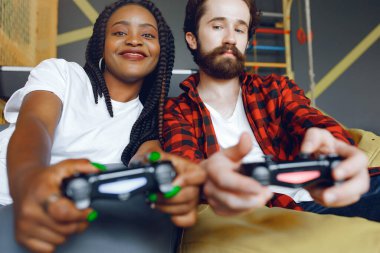 Beyaz tişörtlü siyah kız. Video oyunu oynayan bir çift. İnsanlar joystick kullanır.