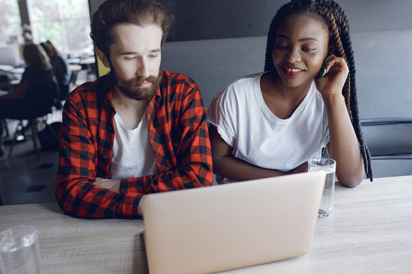 Students create a new project. Couple working in a office. Black girl in a white t-shirt