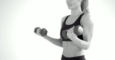 Siyah beyaz resim. Beyaz arka planda spor yapan genç bir kadın.