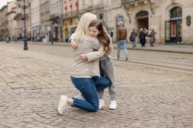 Genç anne kızını kucaklıyor. Kız yanağına Ukrayna bayrağını mavi ve sarı renklerle boyamış. Kadın ve kız Ukrayna 'yı savaşa karşı destekliyor.