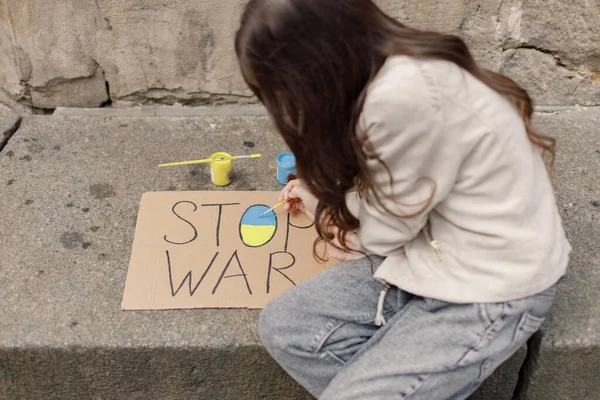 青と黄色のポスターを描く少女 若い可愛い娘がストップ ウォーという言葉を書いてる ウクライナをサポートする女の子 — ストック写真