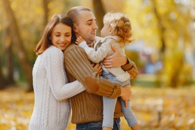 Küçük tatlı kızı olan bir aile. Kahverengi kazaklı baba. Sonbahar tarlasında bir aile
