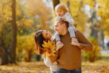 Küçük tatlı kızı olan bir aile. Kahverengi kazaklı baba. Sonbahar tarlasında bir aile