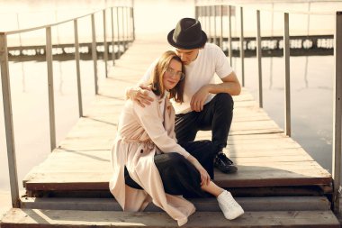 Deniz kenarında bir çift. Beyaz tişörtlü adam. Günbatımı arka planında eşleşin.