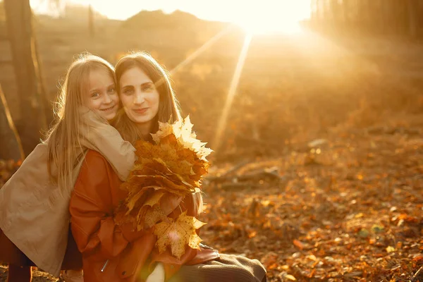 Kızı olan modaya uygun bir anne. Sonbahar parkında bir aile. Kahverengi ceketli küçük kız..