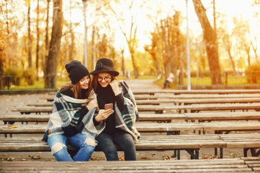 Sonbahar şehrinde oturan iki şık genç kız.