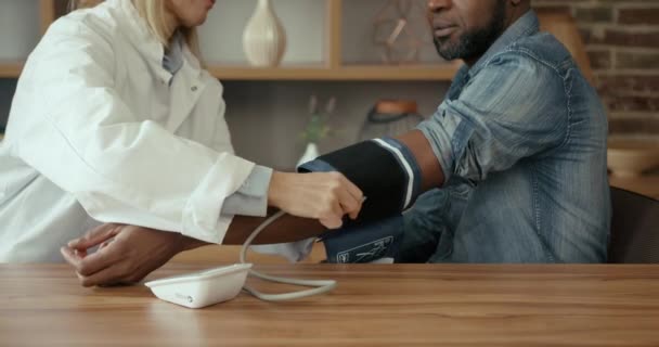 Ärztin Misst Den Blutdruck Eines Jungen Männlichen Patienten Attraktiver Schwarzer — Stockvideo