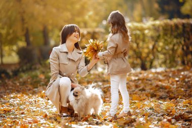 Kızı olan modaya uygun bir anne. Sonbahar parkında bir aile. Köpekli bir aile.