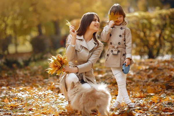 Fashionable mother with daughter. Family in a autumn park. Family with a dog.