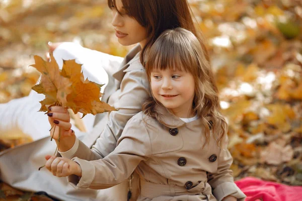 Kızı olan modaya uygun bir anne. Sonbahar parkında bir aile. Kahverengi ceketli küçük kız..
