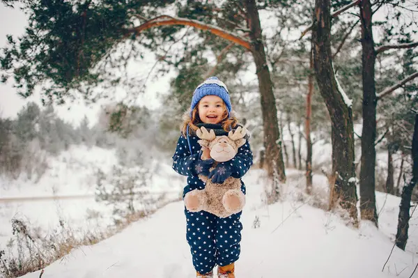 孩子在冬天的森林里 戴蓝帽的女孩 玩玩具的孩子 图库图片