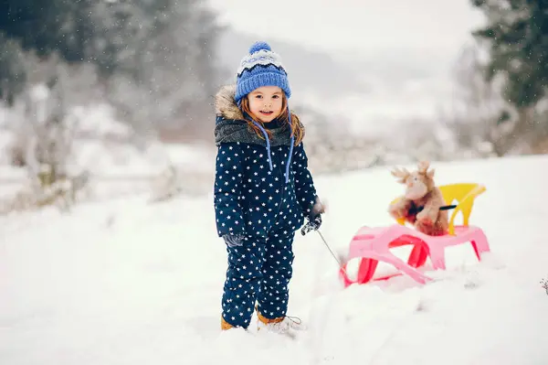 Парень Зимнем Лесу Девушка Синей Шляпе Дети Играют Розовыми Санями Лицензионные Стоковые Фото