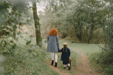 Anne ve kızı köpekle oynuyorlar. Sonbahar parkında bir aile. Evcil hayvan ve yaşam tarzı konsepti. Sonbahar zamanı.