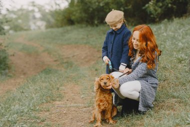 Anne ve kızı köpekle oynuyorlar. Sonbahar parkında bir aile. Evcil hayvan ve yaşam tarzı konsepti. Sonbahar zamanı.