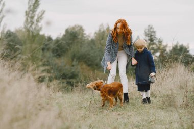 Anne ve kızı köpekle oynuyorlar. Sonbahar parkında bir aile. Evcil hayvan ve yaşam tarzı konsepti. Sonbahar zamanı.