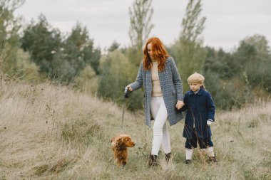 Anne ve kızı köpekle oynuyorlar. Sonbahar parkında bir aile. Evcil hayvan ve yaşam tarzı konsepti. Sonbahar zamanı.