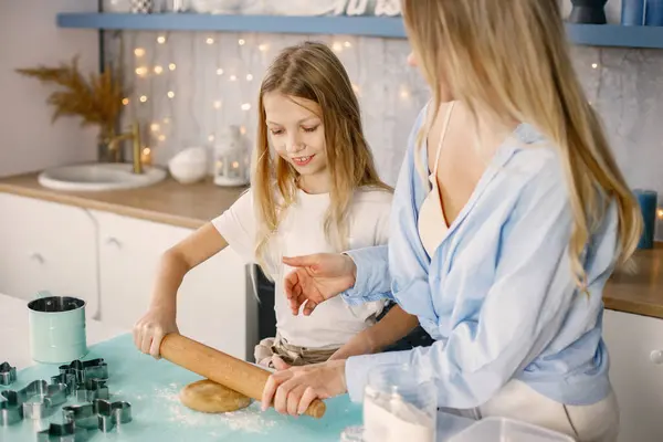 Family preparation of ginger biscuits with daughter. Mother and little girl cooking cookies. Blonde woman wearing blue shirt and girl white t-shirt.